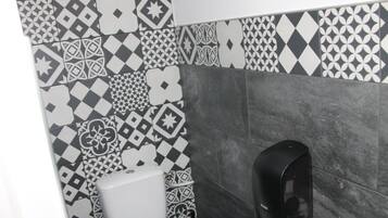 Un baño con azulejos estampados y un dispensador de jabón.