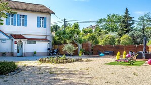 A two-story building with a tiled roof, a small entrance with a sign, and a gravel driveway. - Hôtel Des Moulins (Allauch)