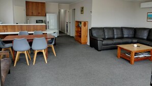Ett kompakt vardagsrum med en matplats, en svart lädersoffa och ett litet träbord.