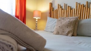 Un lit bien fait, avec une serviette enroulée, une lampe de chevet et un mur orné d’éléments en bois.