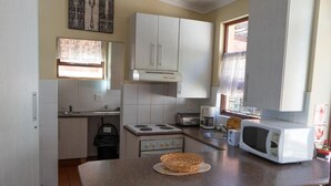 Une cuisine avec des meubles blancs, une cuisinière, un four à micro-ondes et un panier à pain posé sur le comptoir.