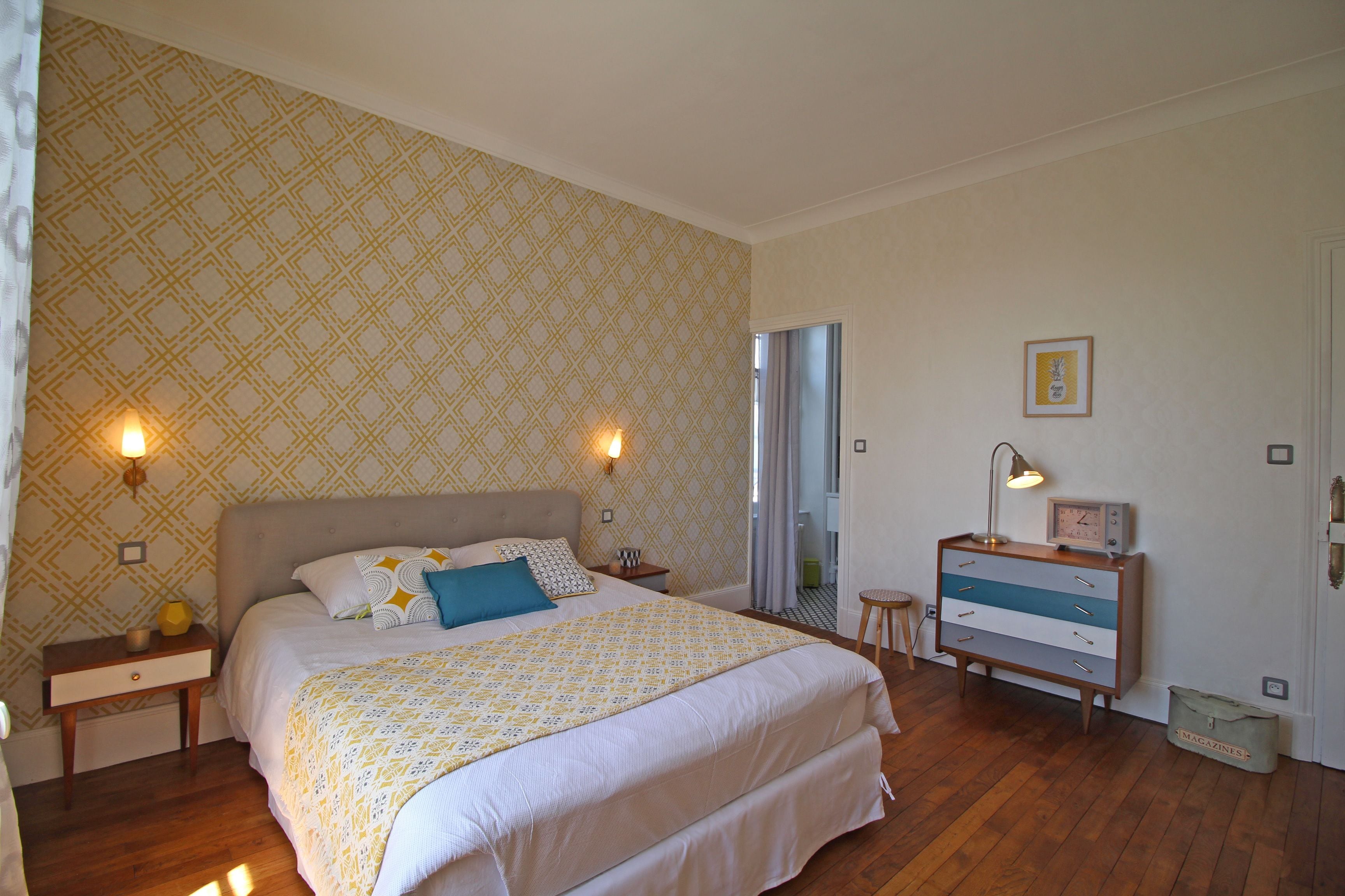 Une chambre à coucher avec un grand lit, des lampes de chevet, une commode et un miroir.