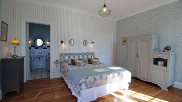Une chambre à coucher avec un lit, une commode et une petite salle de bain visible à travers une porte ouverte.
