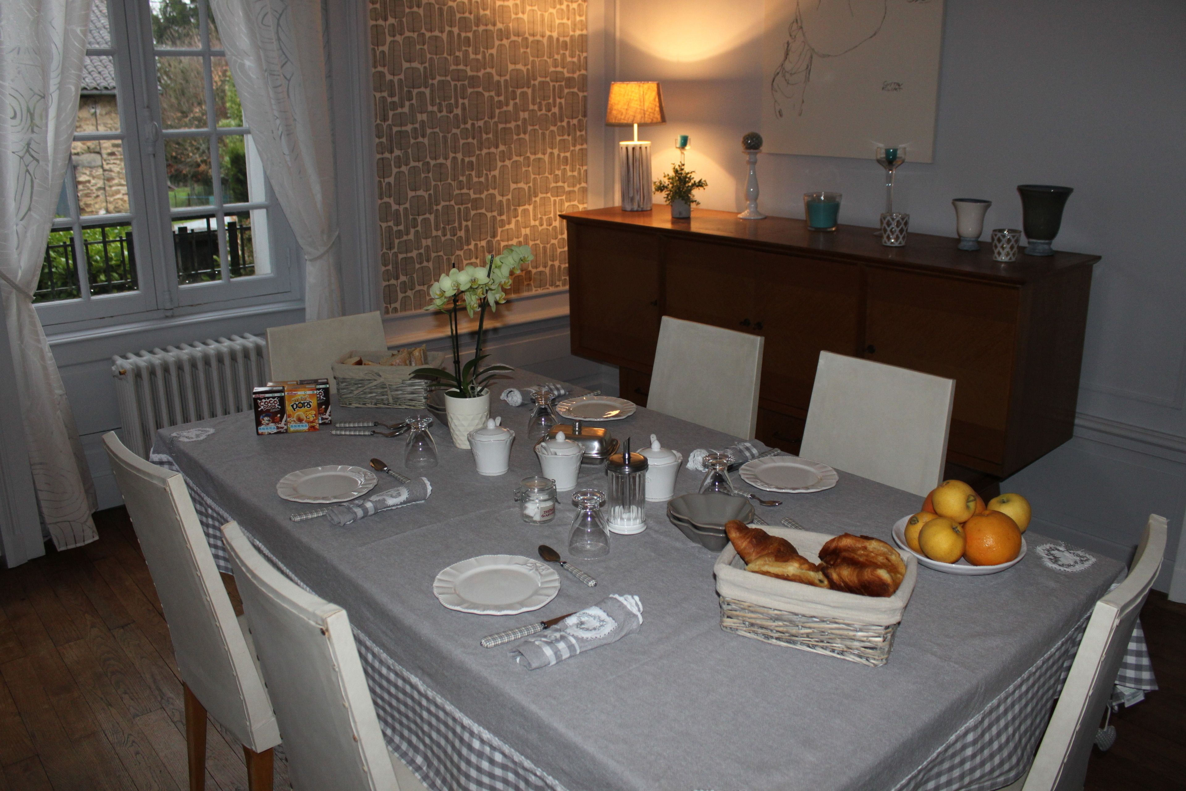 A dining table set with plates, cutlery, and a basket of bread.