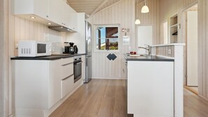 A modern kitchen with white cabinetry, a microwave, a coffee maker, and a sink.