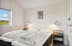 Un dormitorio con una cama, dos mesitas de noche, una ventana y un cuadro colgado en la pared.