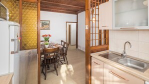 Una cocina con armarios de madera, un lavamanos y una zona de comedor con mesa y sillas.