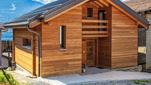 Une cabane en bois avec un toit en pente, une cheminée et un petit porche.