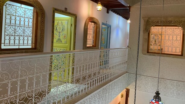A multi-level interior with ornate railings, decorative doors, and hanging light fixtures. - Riad Najiba (Rabat)