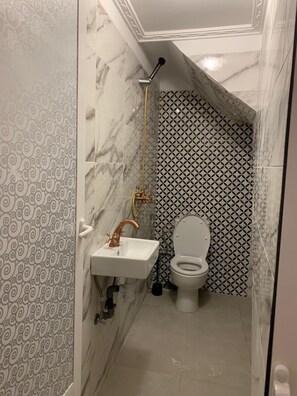 Et badeværelse med vask i marmor, toilet og brusebad.