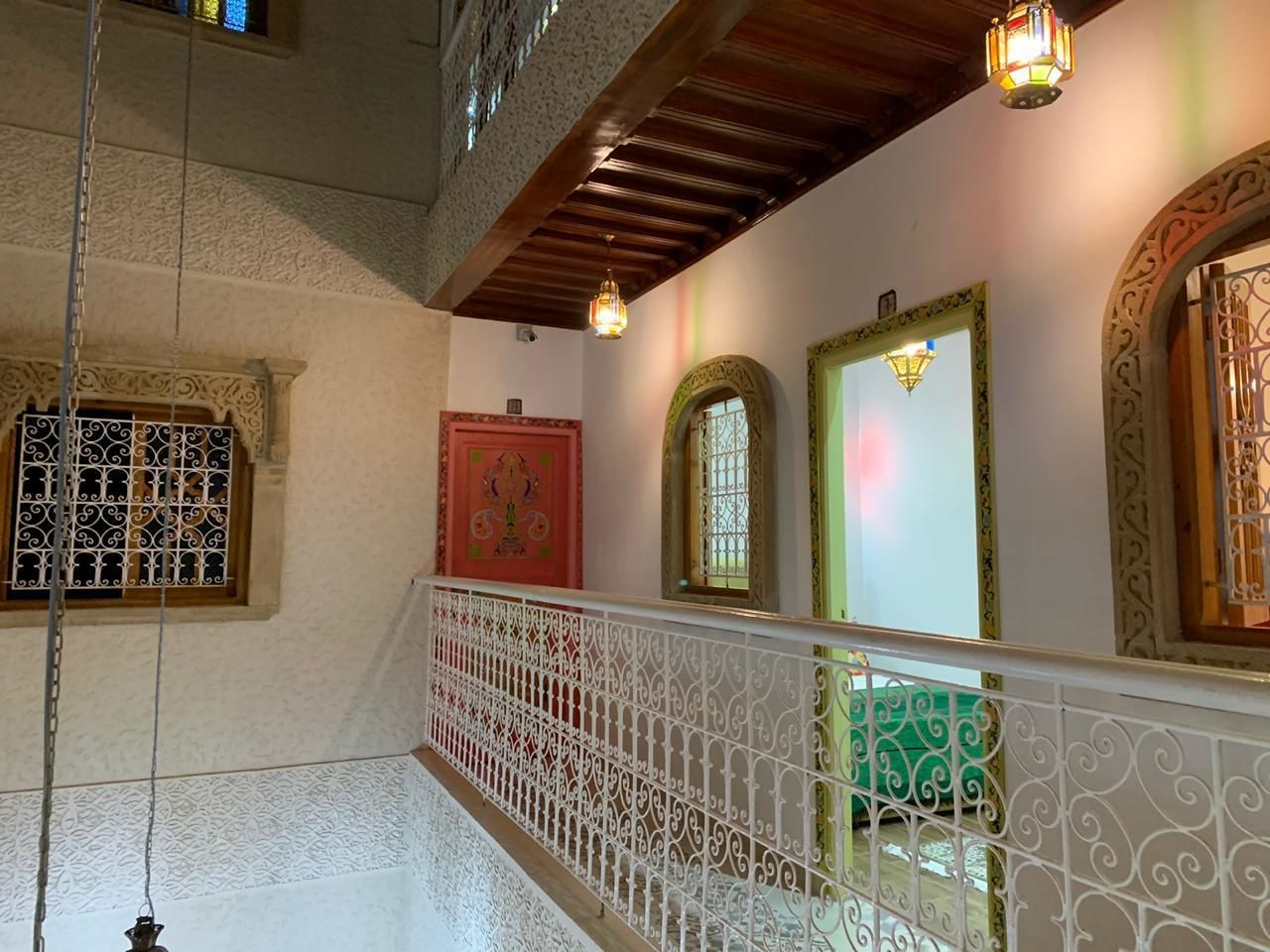 Una escalera con barandillas ornamentadas y detalles decorativos, incluyendo una puerta roja y una pared verde.