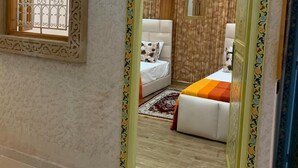 A room with a bed, a window, and a mirror with a decorative frame. - Riad Najiba (Rabat)