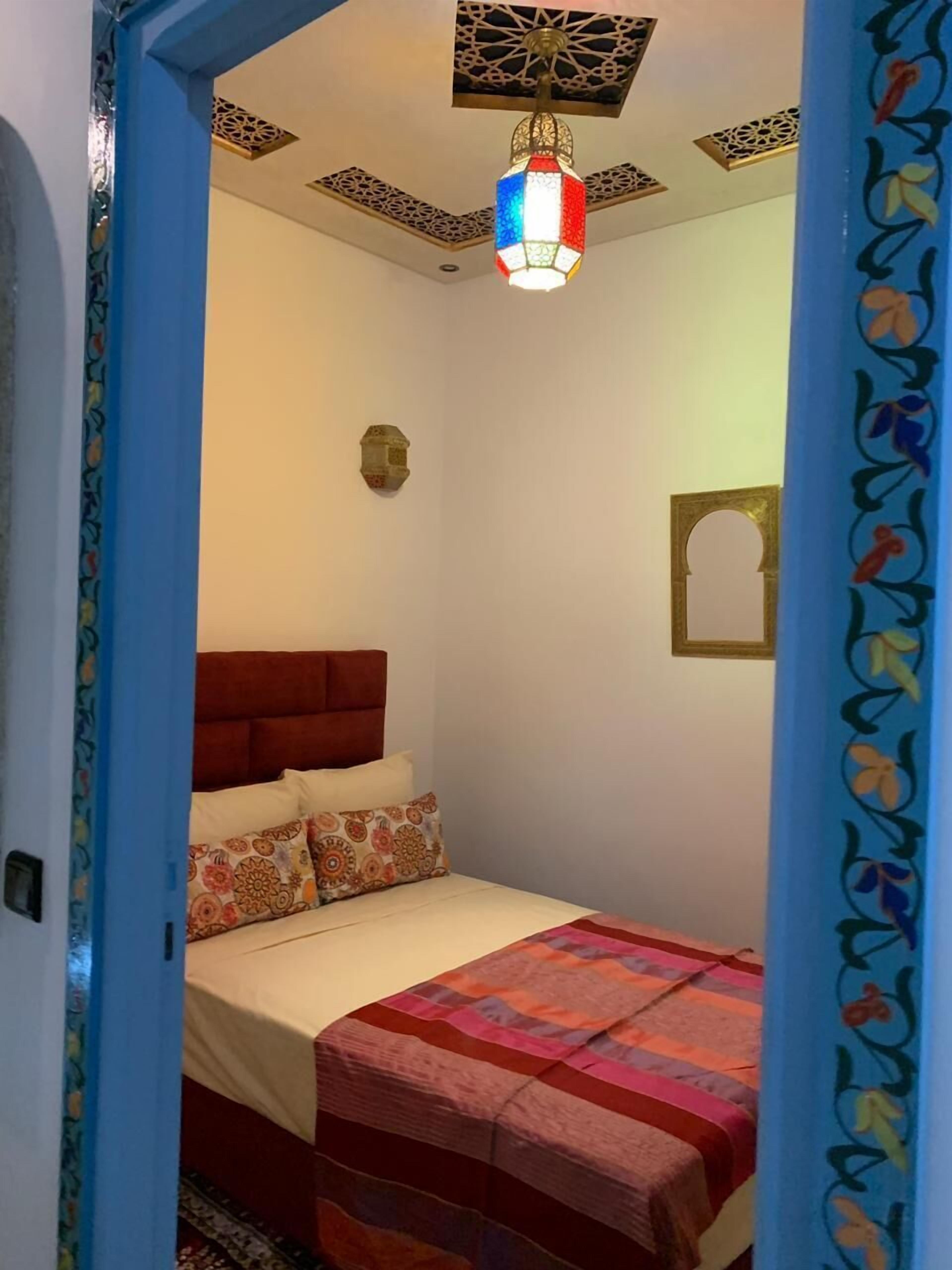 A bedroom with a bed, a decorative ceiling light, and a wall-mounted mirror.