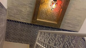 A staircase with ornate metal railings and a decorative wall with a patterned tile design. - Riad Najiba (Rabat)