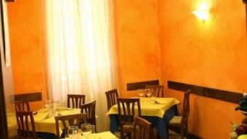 Un comedor con mesas preparadas para dos personas, un cuenco de fruta y botellas de vino sobre la mesa.