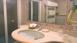 Ein Badezimmer mit einem beigen Waschbecken, einem Spiegel und einem Handtuchhalter.
