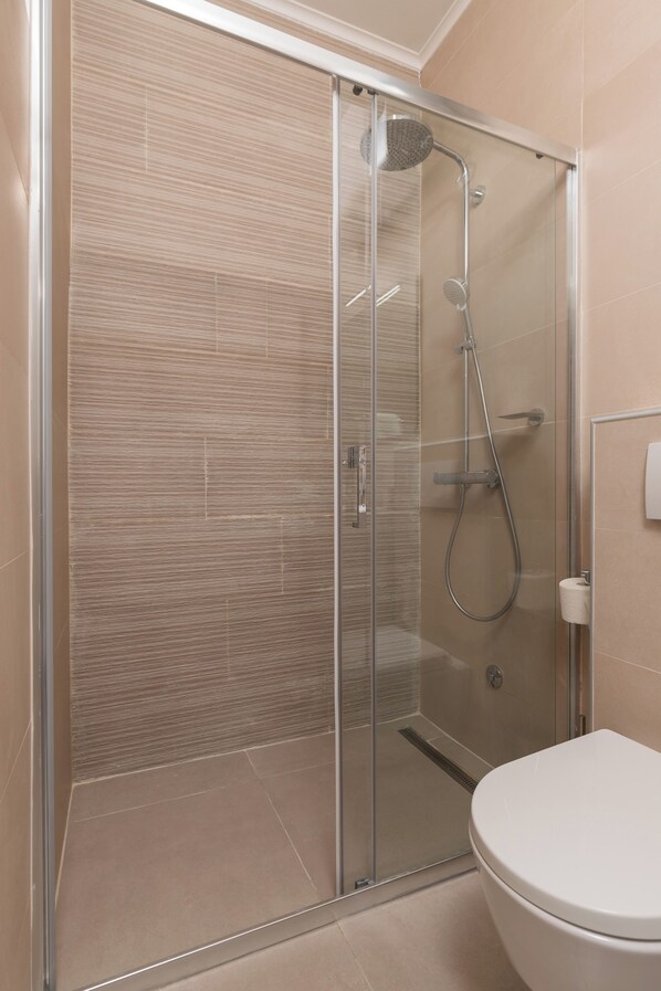 A modern bathroom with a glass-enclosed shower, a toilet, and a sink.