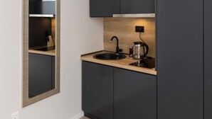 Une cuisine moderne avec des meubles de couleur sombre, un four à micro-ondes encastré et un plan de travail en bois.