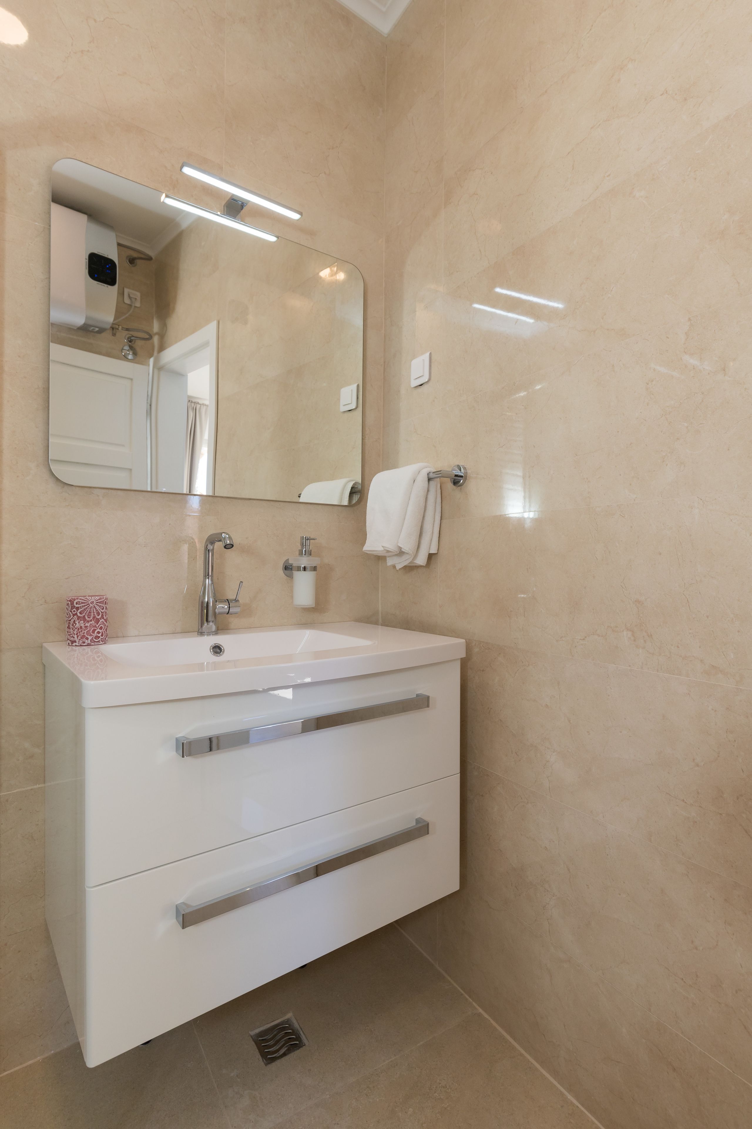 Une salle de bain moderne avec un meuble-lavabo blanc, un grand miroir et un porte-serviettes.