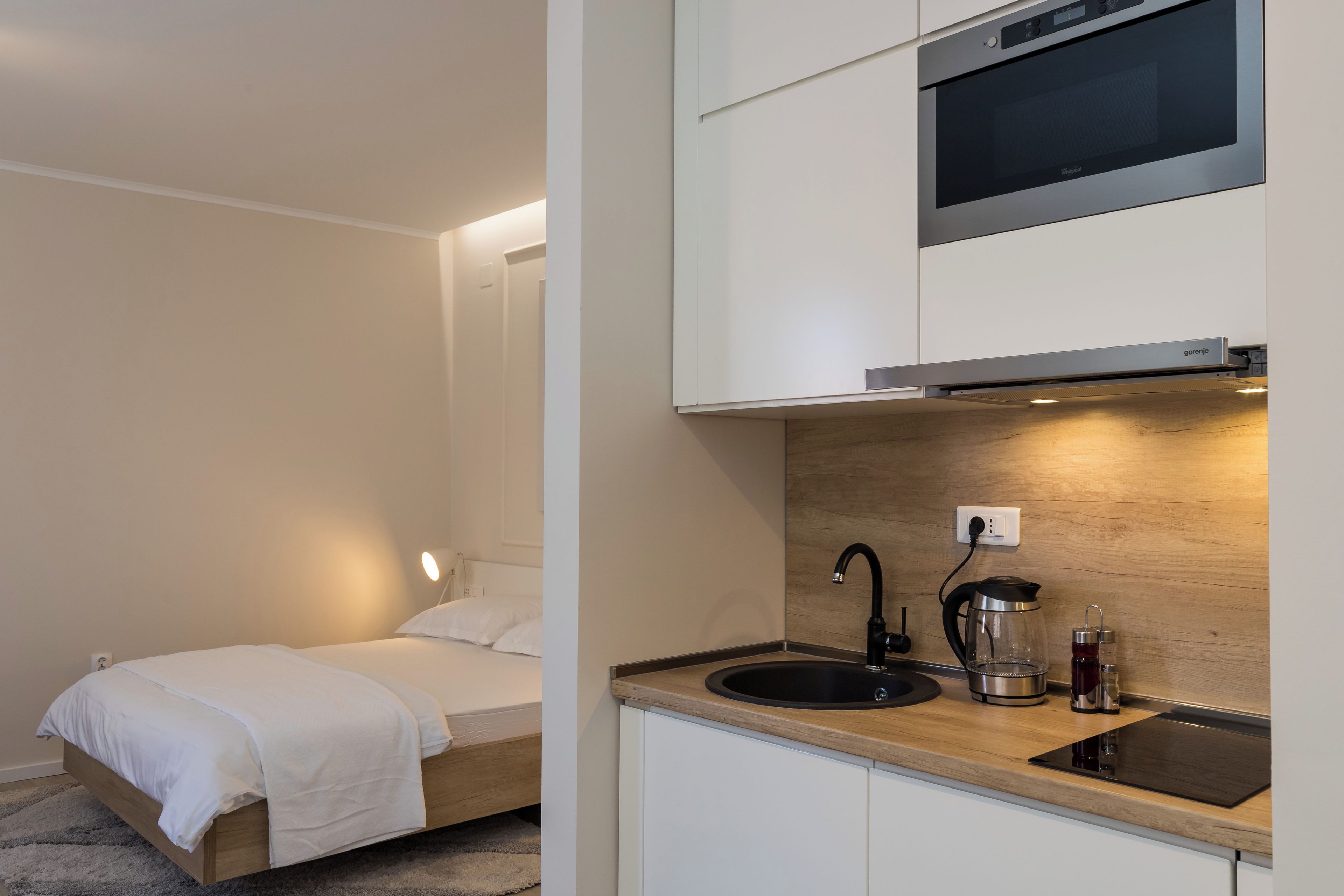 A compact bedroom with a single bed and a small kitchenette.