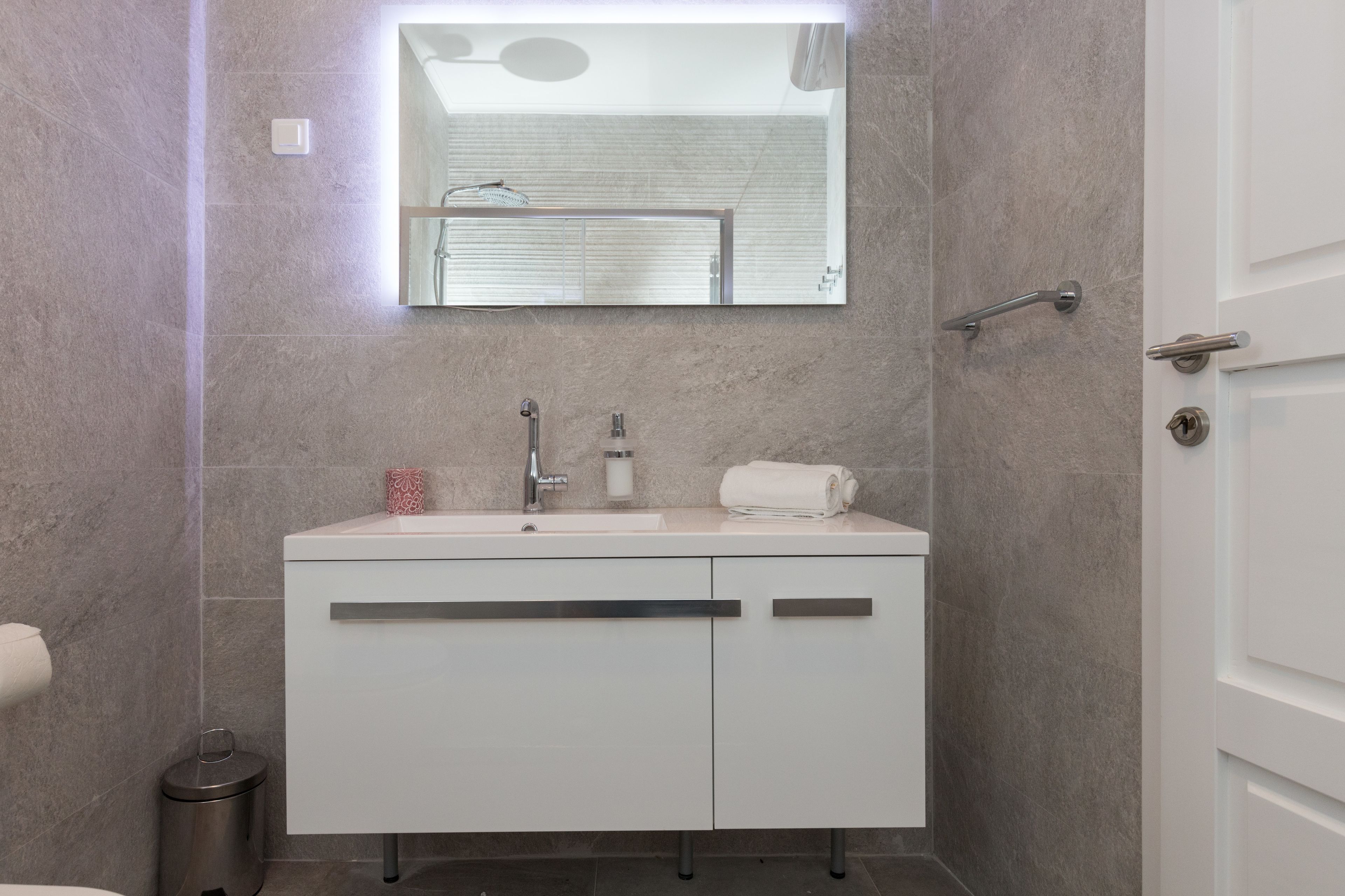 A modern bathroom with a white vanity, a mirror, and a shower.