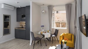 Une cuisine moderne avec des meubles de couleur grise, une table à manger avec des chaises et un fauteuil jaune.