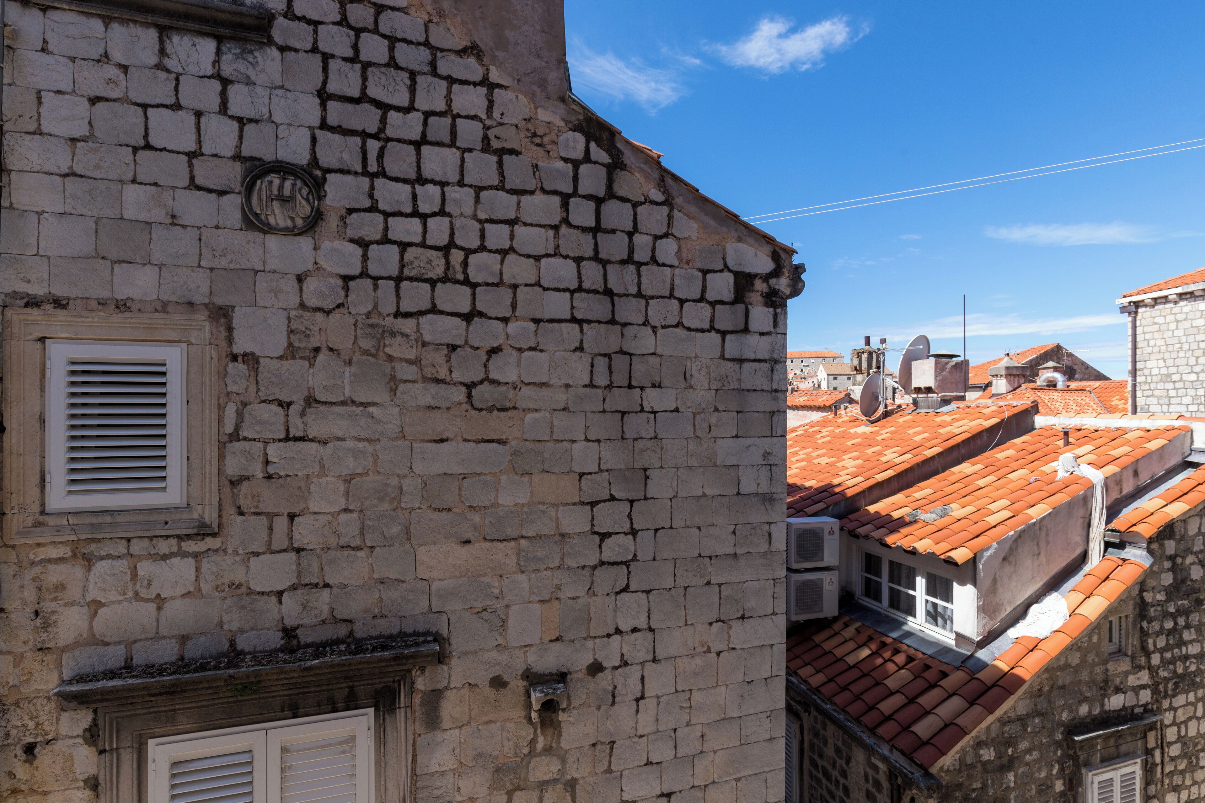 A stone building with a visible air conditioning unit and a window with shutters.