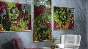 A room with a marble wall, two framed abstract paintings, a purple armchair, a white armchair, and a small table with a vase. - Marinn Deluxe Hotel (Altinova)