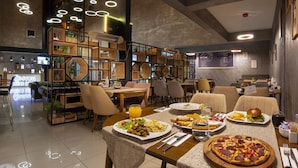 A modern restaurant with a high ceiling, circular lighting, and a variety of seating options. - Marinn Deluxe Hotel (Altinova)