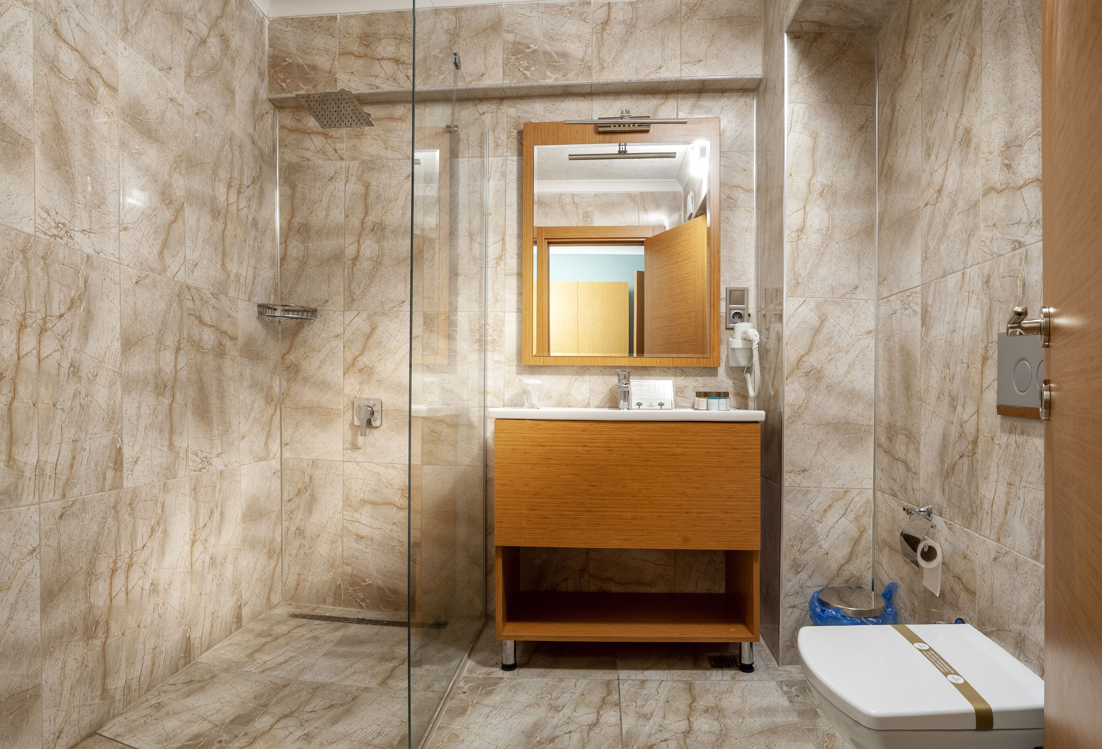 A modern bathroom with a glass shower enclosure, a wooden vanity, and a toilet.