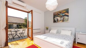 A bedroom with a large bed, a painting on the wall, and a balcony with a table and chairs. - Romance Apartment Dubrovnik (Dubrovnik)