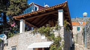 A stone building with a tiled roof, a small outdoor seating area, and a staircase leading to the upper floor. - Romance Apartment Dubrovnik (Dubrovnik)