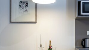 A modern kitchen with white cabinetry, a dining table with chairs, a framed artwork on the wall, and a pendant light above the table. - Romance Apartment Dubrovnik (Dubrovnik)
