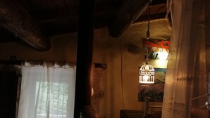 A rustic interior with a wooden ceiling, a hanging lantern, and a window with sheer curtains. - Agriturismo Arcera (Roccafluvione)