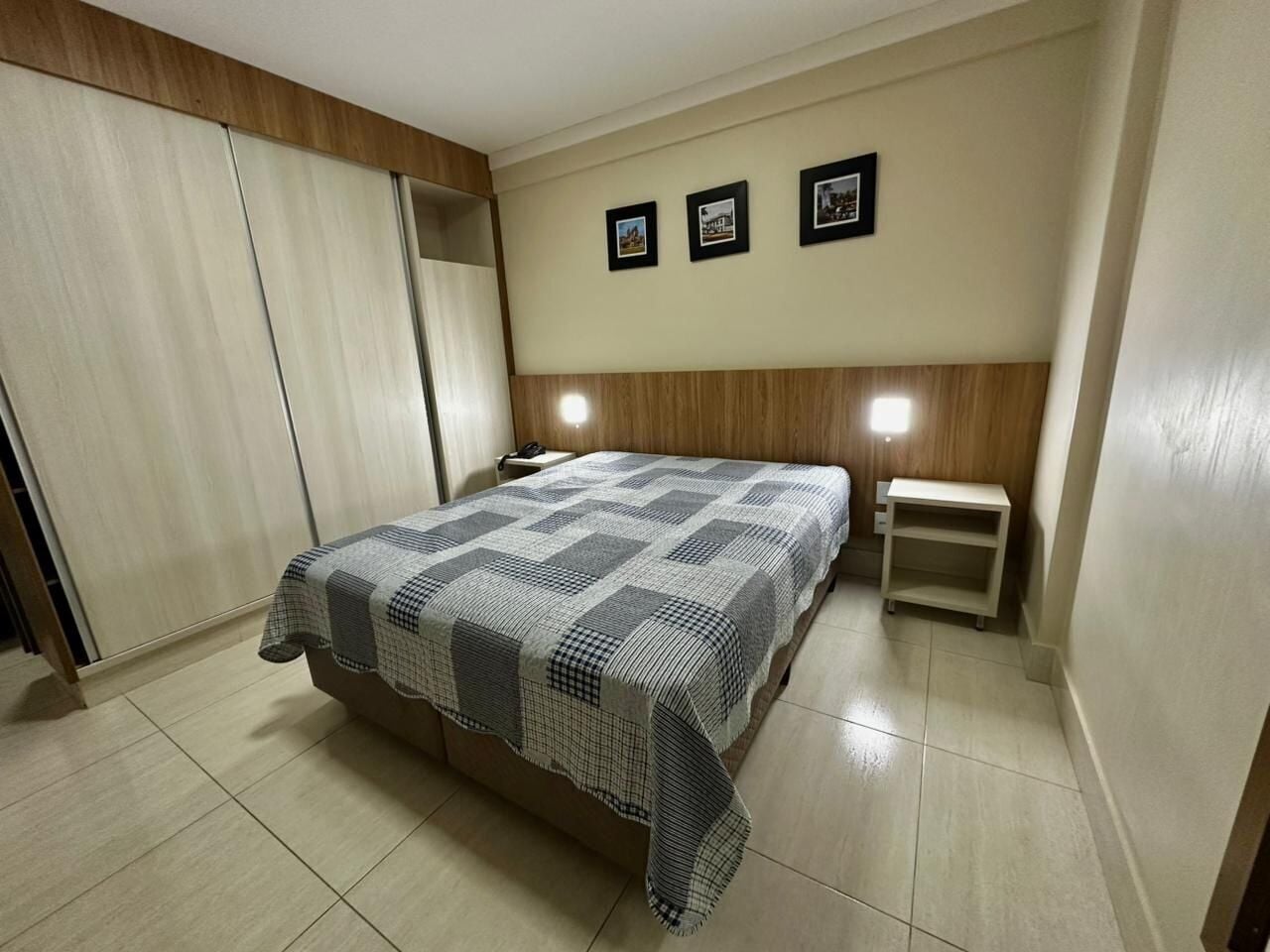 A bedroom with a bed, bedside tables, a wardrobe, and framed pictures on the wall.