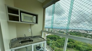 Un balcó amb zona de cuina, que inclou un rentaplat i un forn microones, i vista a paisatge urbà.