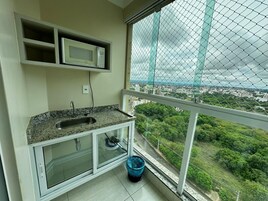 Varanda com cozinha, incluindo pia e micro-ondas, e vista para a cidade.