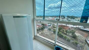 Uma varanda com vista para a paisagem urbana, uma geladeira branca e um balde azul.