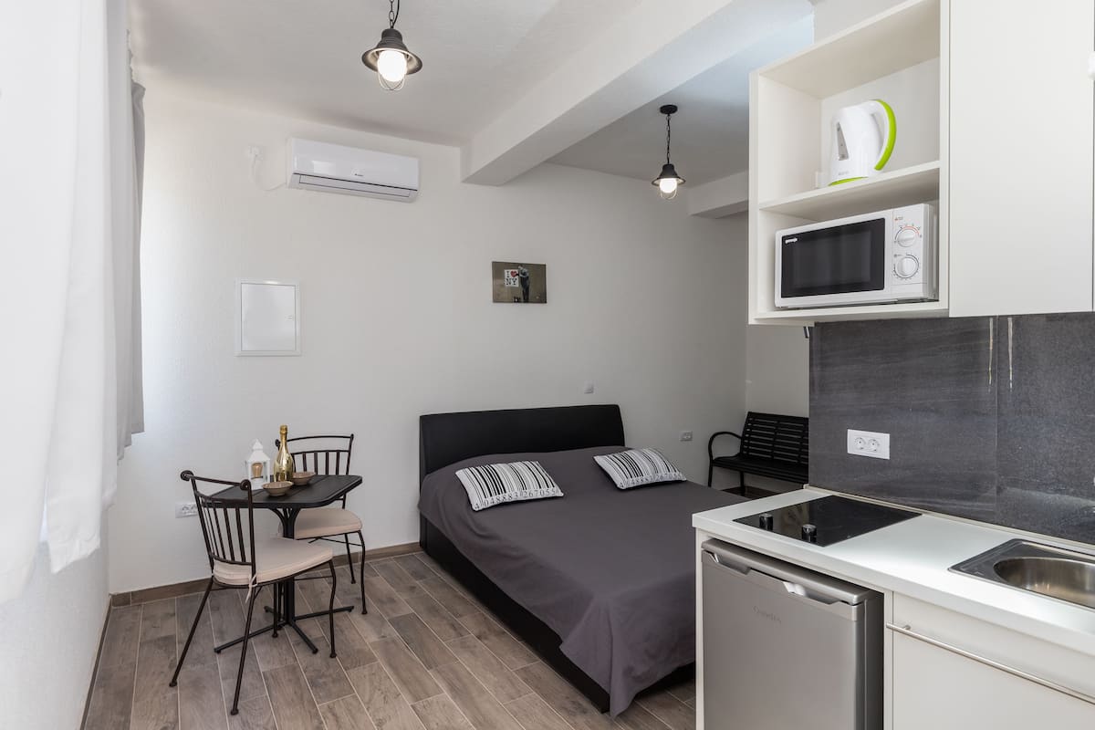 Une pièce de taille modeste comprenant un lit, une petite table avec des chaises, un four à micro-ondes et un lave-vaisselle.