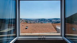A view from a window with a clear sky, a cityscape with red-roofed buildings, and a distant mountain range. - Apartments Life (Dubrovnik)