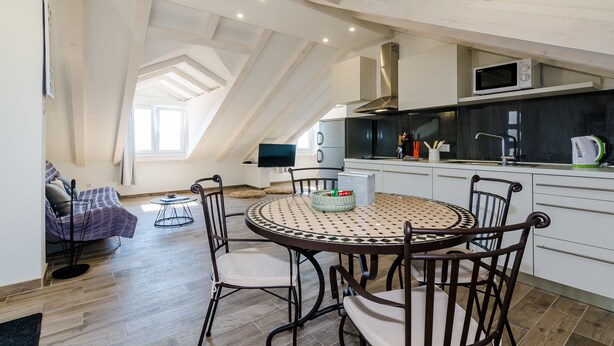A modern kitchen with a round dining table, white cabinets, and a built-in microwave. - Apartments Life (Dubrovnik)