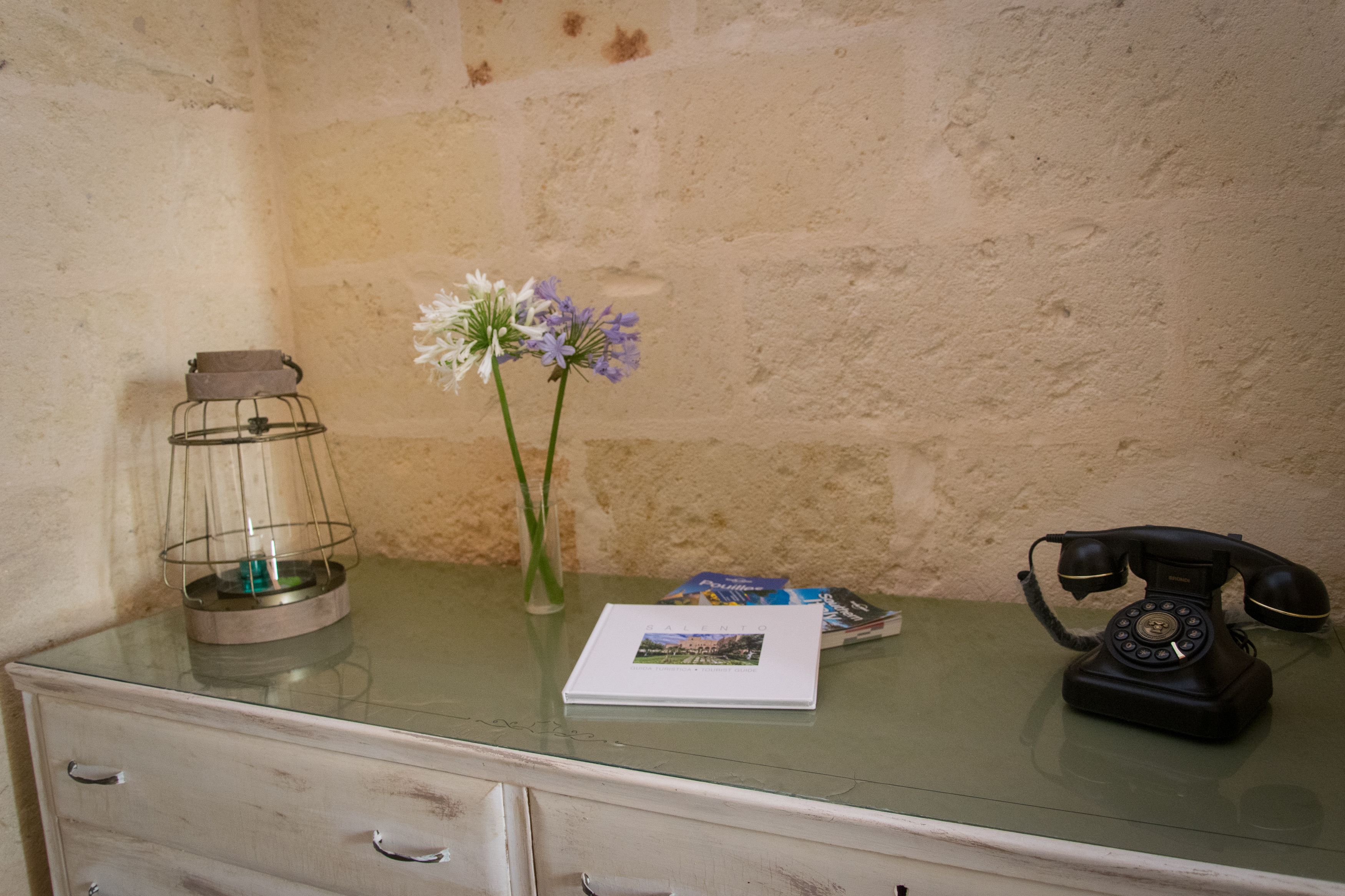 Un bureau agrémenté d’un téléphone ancien, d’un chandelier et d’un vase rempli de fleurs.
