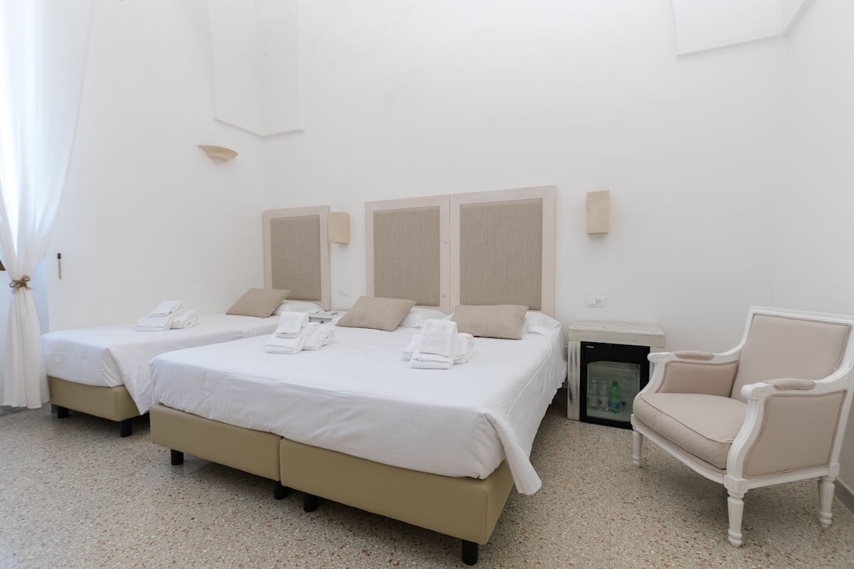 A hotel room with two beds, a chair, and a small table.