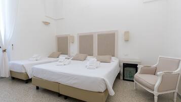 A hotel room with two beds, a chair, and a small table.