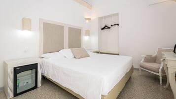 Une chambre d’hôtel équipée d’un lit, d’un petit réfrigérateur, d’une chaise et d’un porte-manteau fixé au mur.