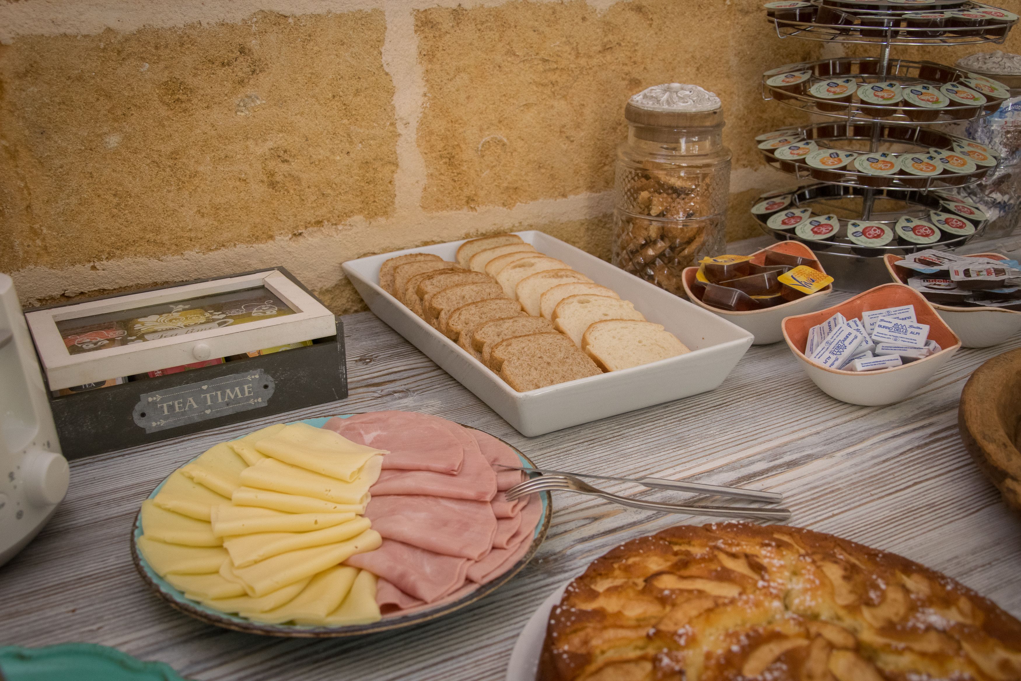 A buffet table with various food items including sliced bread, pastries, and a ham and cheese platter.