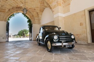 Un coche antiguo estacionado bajo un arco de piedra con un farol colgante.