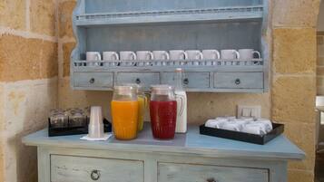 A breakfast bar with a light blue color scheme, featuring a milk jug, two pitchers of orange and red beverages, and a tray of white cups.
