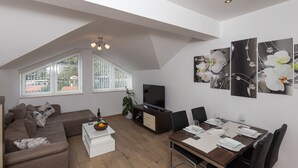 A modern living room with a sofa, dining table, and TV. - Villa Celenca (Dubrovnik)