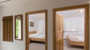 A room with two wooden beds, a mirror, and a door leading to another room. - Villa Celenca (Dubrovnik)